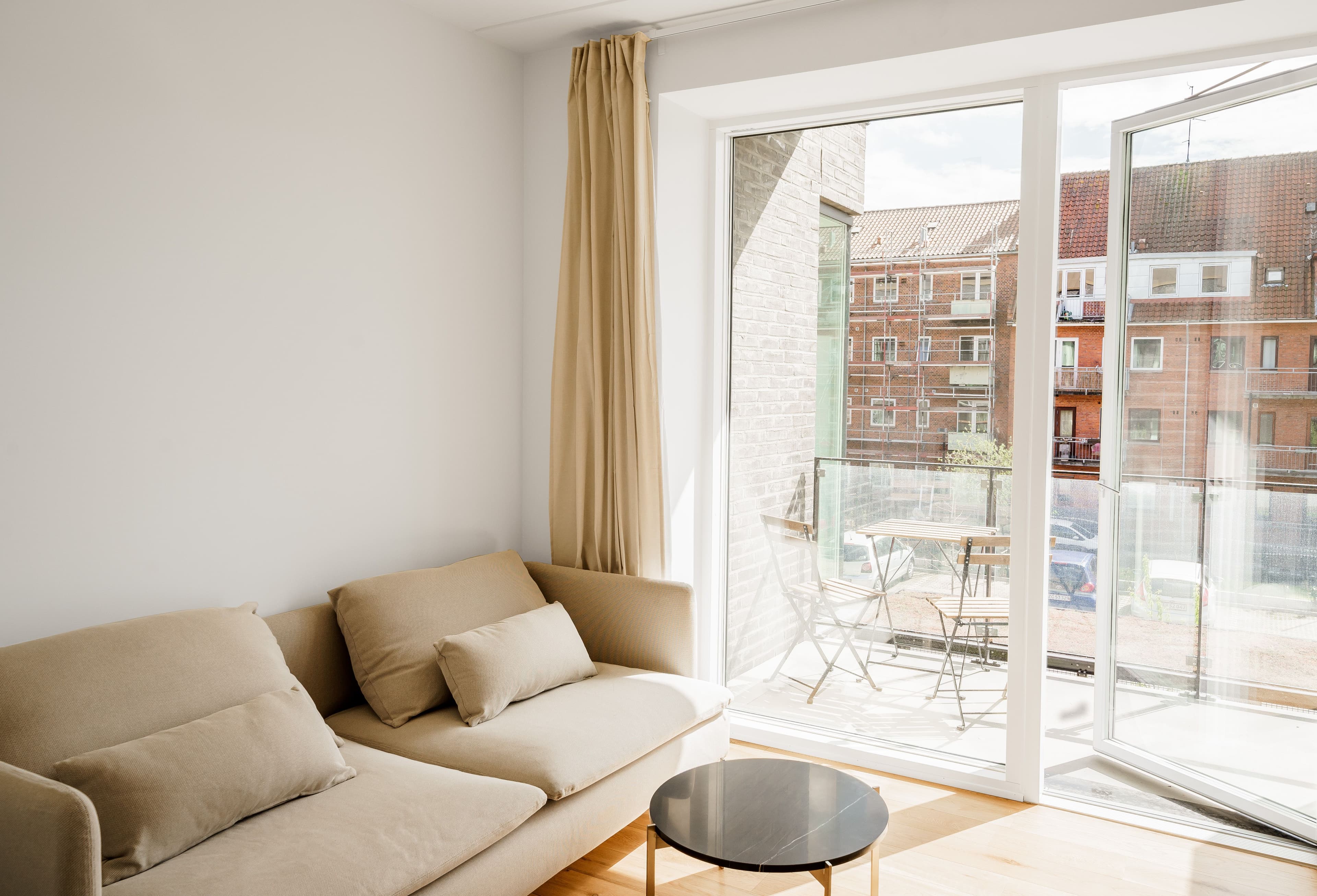 A livingroom with a balcony looking out on buildings in copenhagen