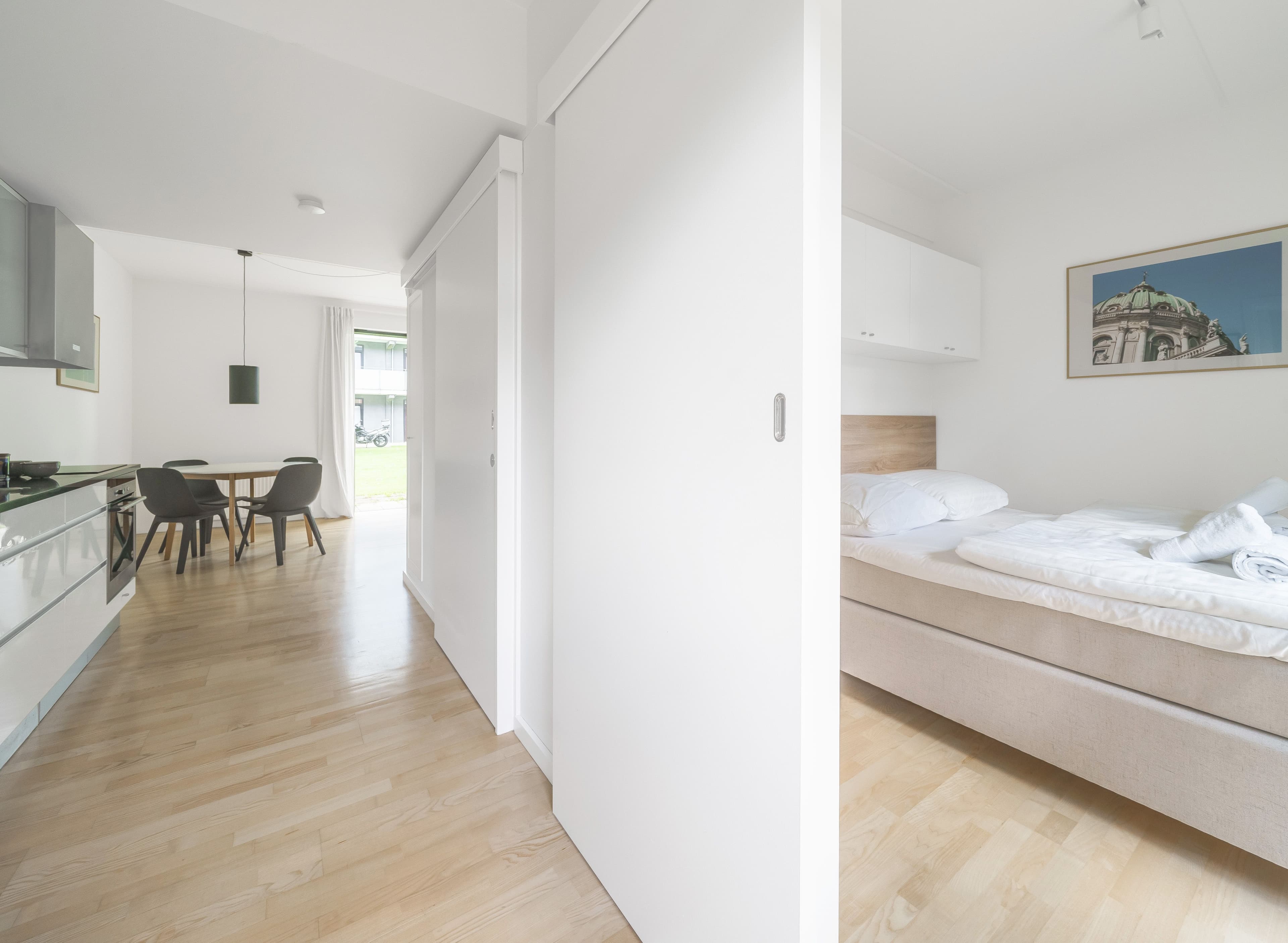 A view of a dining table and a bedroom through a hallway