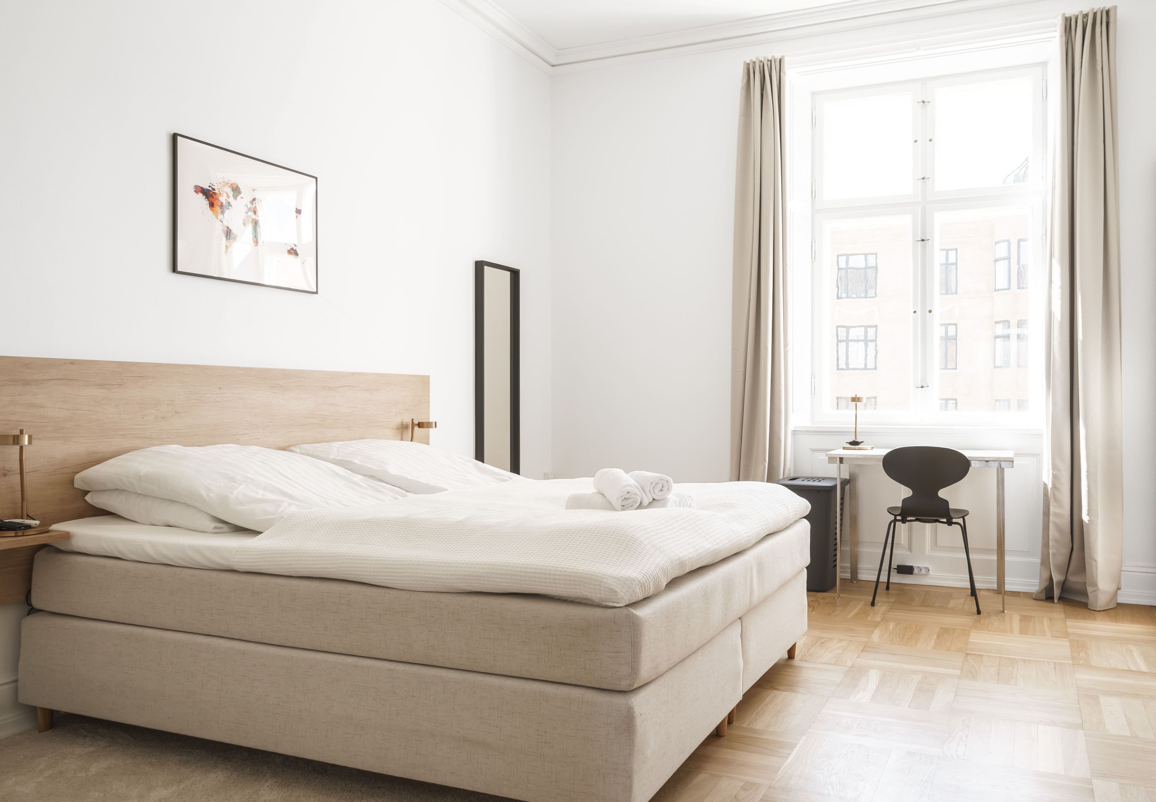 A bedroom with a small white desk and a bed
