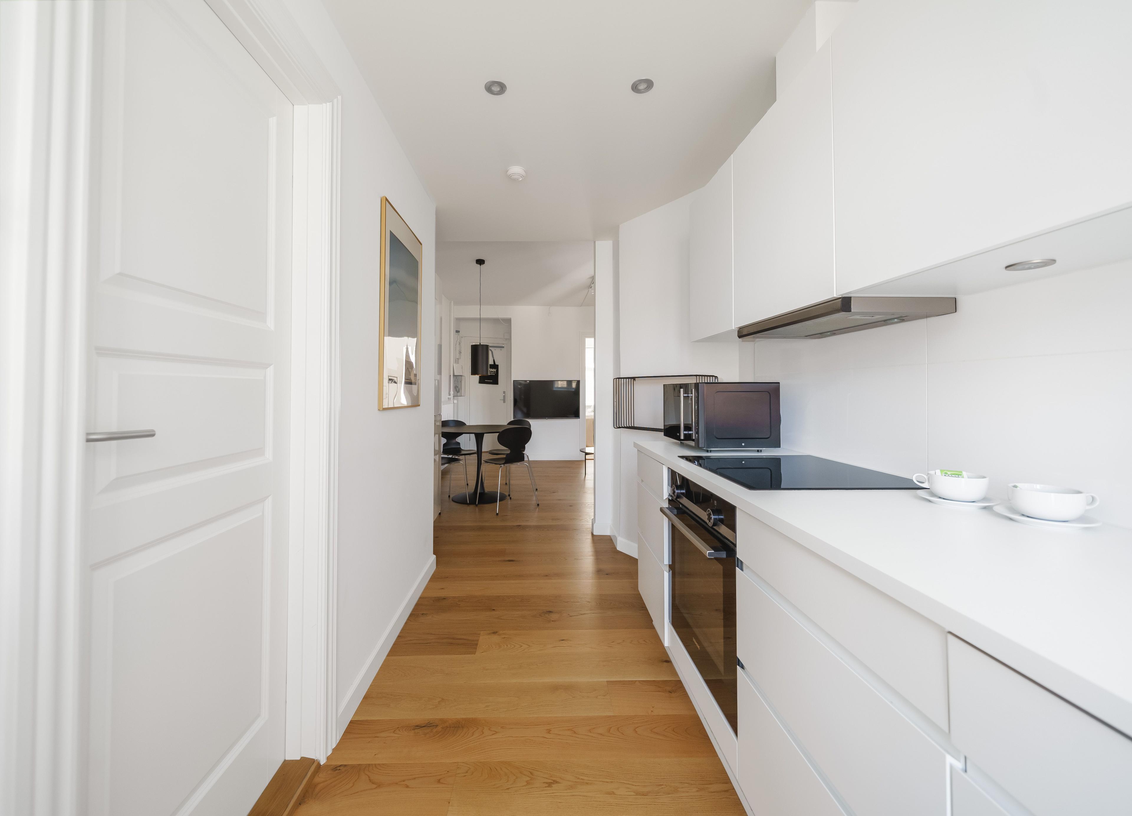 En korridor med ett kök med en vit bänkskiva