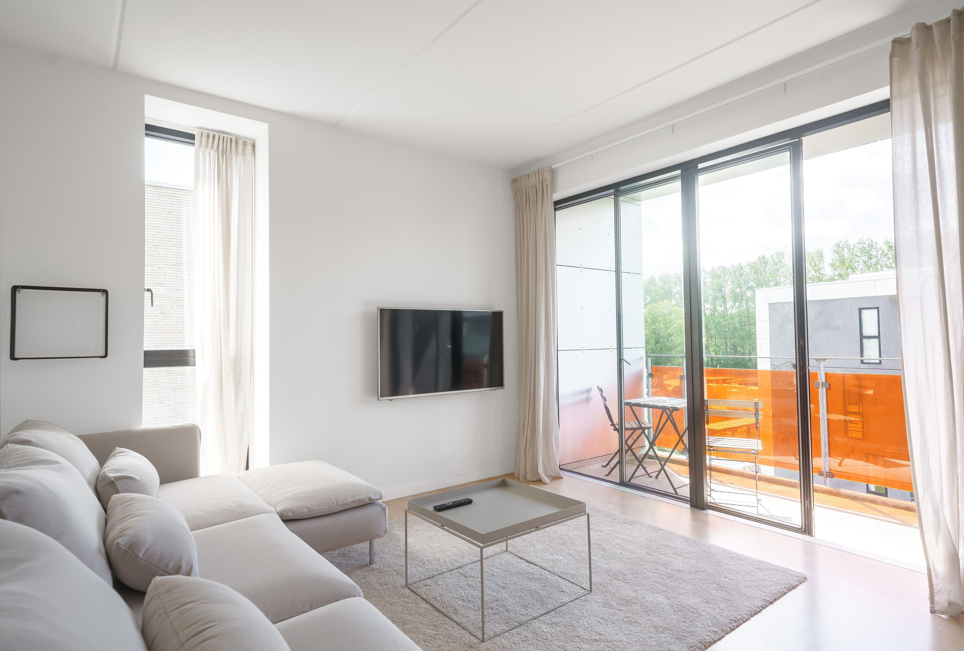A livingroom leading into a balcony with orange glass panes
